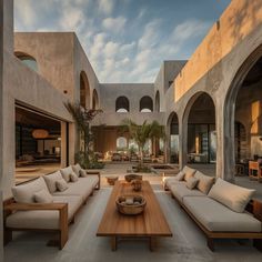 an outdoor living area with couches and tables in the center, surrounded by arches