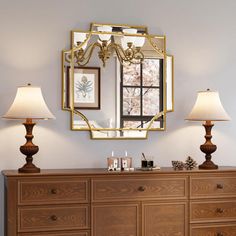 a dresser with two lamps and a mirror on the wall