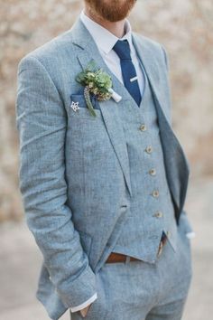 a man with a beard wearing a gray suit and flower boutonniere on his lapel