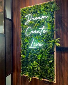 a sign that says dream create live on the side of a wall covered in plants