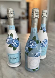 three bottles with blue flowers on them sitting on a counter top next to each other