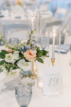 a table with candles and flowers in vases on top of the tables at a wedding reception