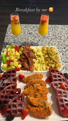 the breakfast platter is ready to be eaten with fruit, eggs, waffles and juice