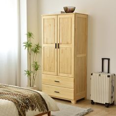 a bedroom with a bed, dresser and luggage bag next to the window in front of it