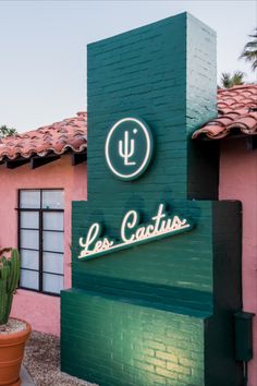 the sign for lees cactus is displayed in front of a pink building with green trim