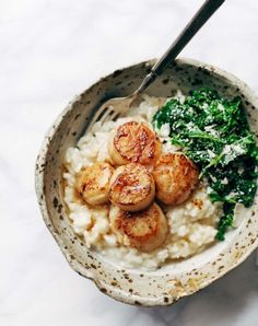 a bowl filled with rice and scallops on top of a table