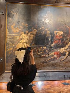 a woman taking a photo of a painting