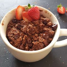 a close up of a bowl of food with chocolate chips and strawberries on the side