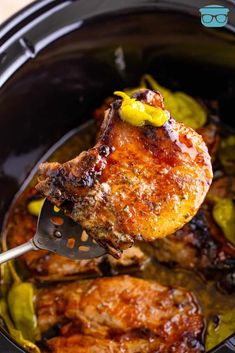 the meat is being cooked in the crock pot with a spatula and sauce