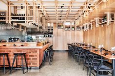 an empty restaurant with tables and stools in front of the counter, filled with wine glasses