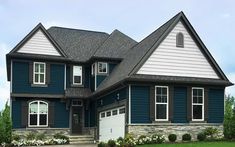 a large blue house with white trim and black shutters on the front door is shown