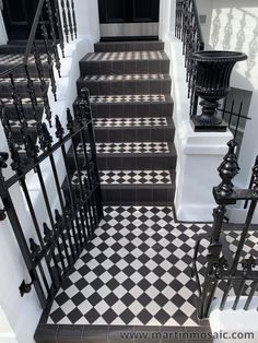 black and white tiled stairs with wrought iron railings