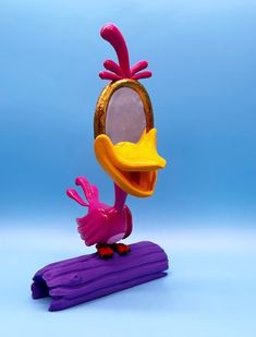 a pink and yellow bird is standing on a purple object