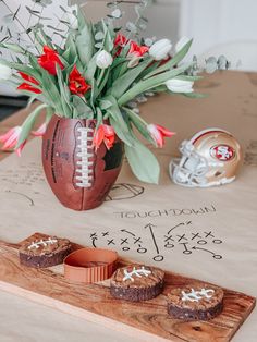 a football themed tray with cupcakes and flowers in the center on a table