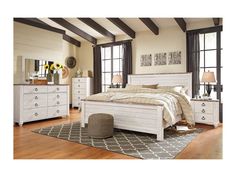 a white bed sitting on top of a wooden floor next to a dresser and mirror