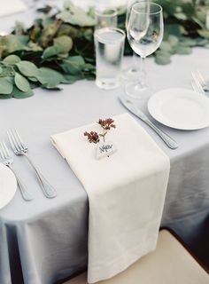 the table is set with white plates and silverware, napkins and place settings