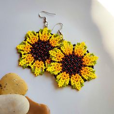 a pair of yellow and black seed beaded earrings on top of a white surface