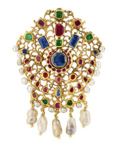 This historic gold brooch hails from the illustrious Mughal Empire and showcases the beauty of traditional jadau jewelry. Using the jadau technique, artisans create a gold frame into which precious stones and other treasures can be imbedded. Almost certainly once worn as adornment for a turban or other head covering, the creation has been modified to be wearable as both a pendant and brooch. The 14K yellow gold brooch showcases colored gemstones with vibrant red, green and blue hues, as well as Mughal Empire Jewelry, Traditional Yellow Gold Pendant Brooches, Traditional Ceremonial Brooch Jewelry, Traditional Gemstone Brooches For Gift, Traditional Gemstone Brooches As Gift, Mughal Jewelry Royals, Mughal Jewellery, Jadau Jewelry, Mughal Jewelry