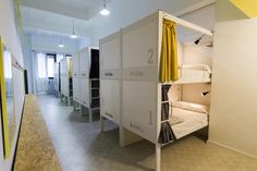 bunk beds are lined up against the wall in a room with white walls and yellow curtains