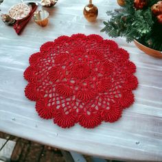 a red doily sitting on top of a white table next to potted plants