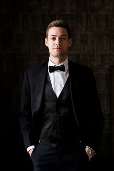 a man in a tuxedo is posing for a photo with his hands in his pockets