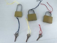 four padlocks with keys attached to them on a white surface, one is yellow and the other is red