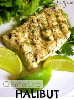 a white plate topped with fish and limes next to lettuce on top of it