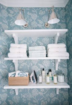 two white shelves with towels and other items on them