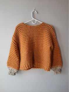 an orange sweater hanging on a white hanger