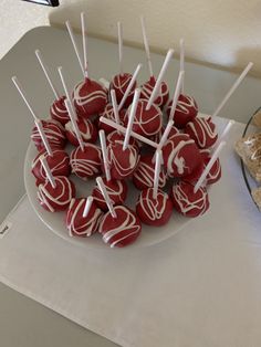 there are many red and white candies on the plate with toothpicks in them