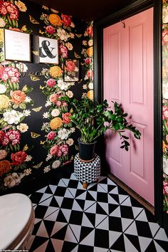 a potted plant sitting in front of a pink door next to a black and white checkered floor