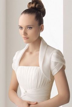 a woman wearing a white dress with a high bun