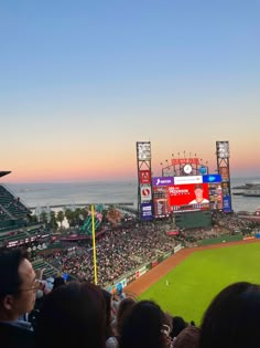 a baseball stadium filled with lots of people sitting on the bleachers at sunset