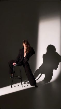 a woman sitting in a chair with her shadow on the wall