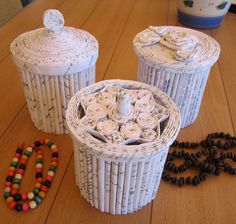 three white containers sitting on top of a wooden table next to beaded bracelets