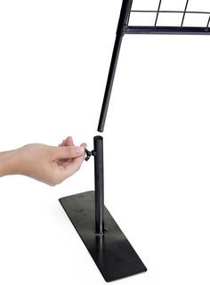 a hand is holding the handle on a black metal stand that holds a computer monitor