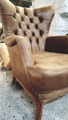 a brown leather chair sitting on top of a floor