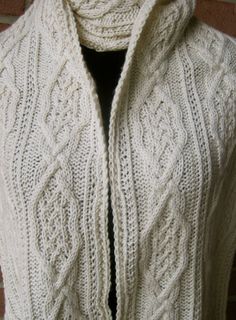 a white knitted sweater hanging up against a brick wall