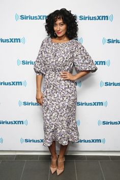 a woman standing in front of a wall with the sirius logo on it's side