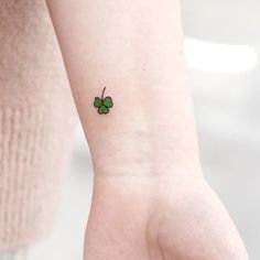 a small four leaf clover tattoo on the left inner wrist, with a green shamrock in the middle