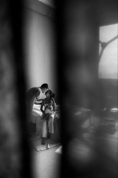 a man and woman standing in front of a bed with their arms around each other