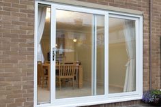 an open sliding glass door in front of a brick wall with a table and chairs