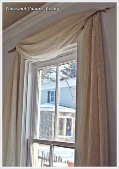 an open window with white curtains in front of it