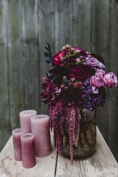 purple flowers and candles sit on a wooden table