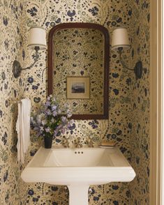 a white sink sitting under a bathroom mirror next to a wall mounted faucet