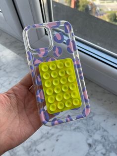 a hand holding a cell phone case with yellow circles on the front and purple dots on the back