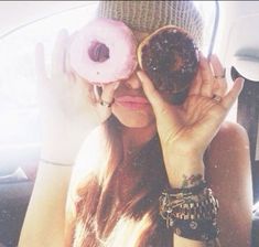 a woman holding two doughnuts up to her eyes while sitting in a car