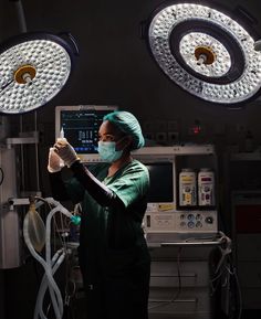 a woman in scrubs and surgical gloves operating lights