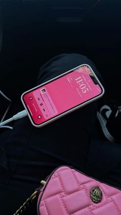 a pink cell phone sitting on top of a purse