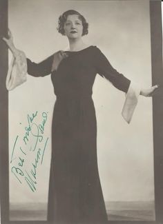 an old black and white photo of a woman in a long dress with her arms outstretched